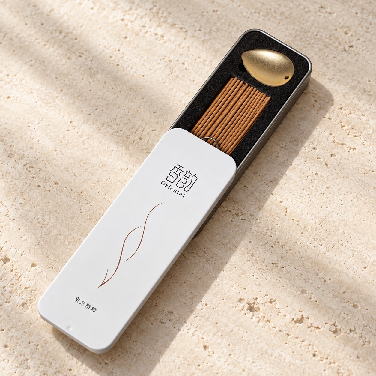 White sliding incense tin with brown incense sticks and a small gold-colored holder